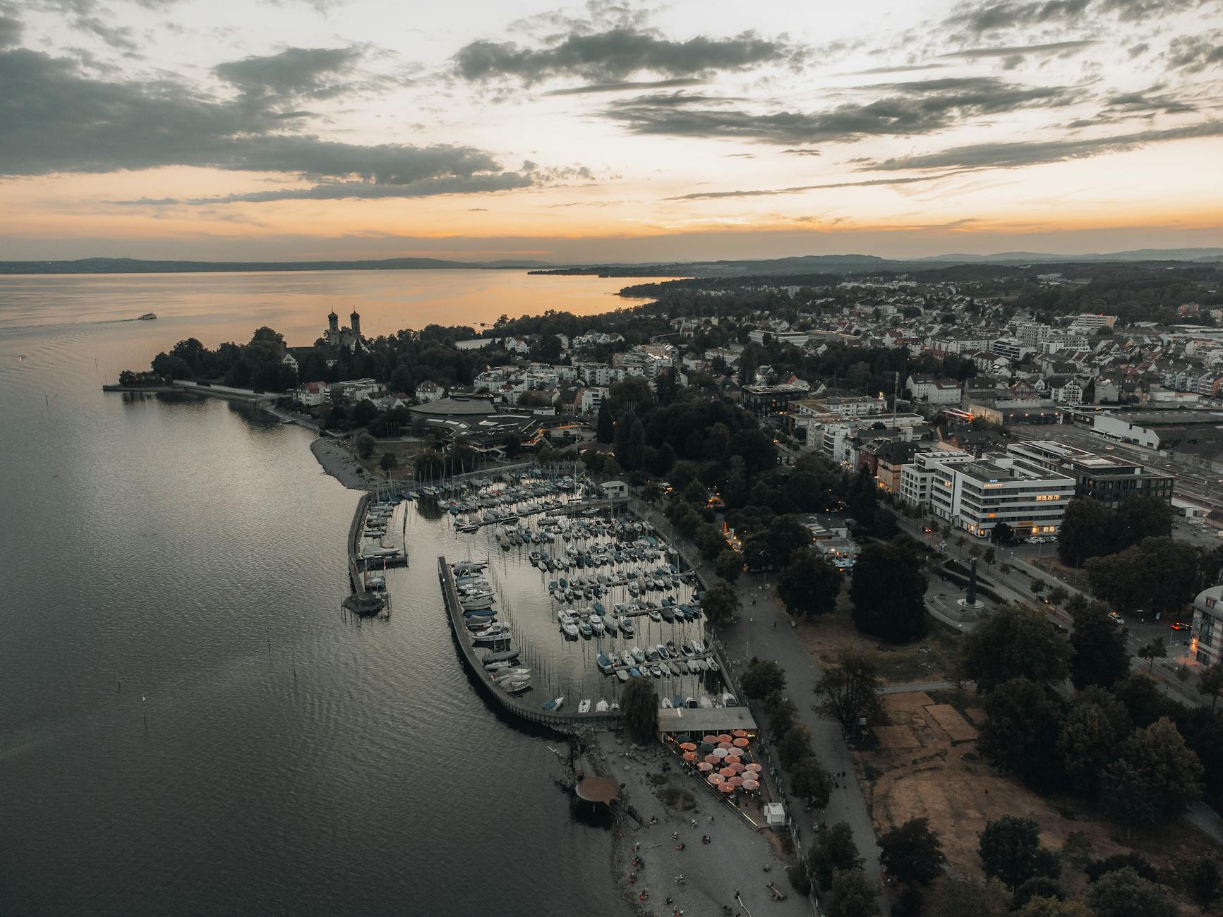 Beautiful aerial view of Friedrichshafen harbor during a dramatic sunset, showcasing the scenic town and calm waters.