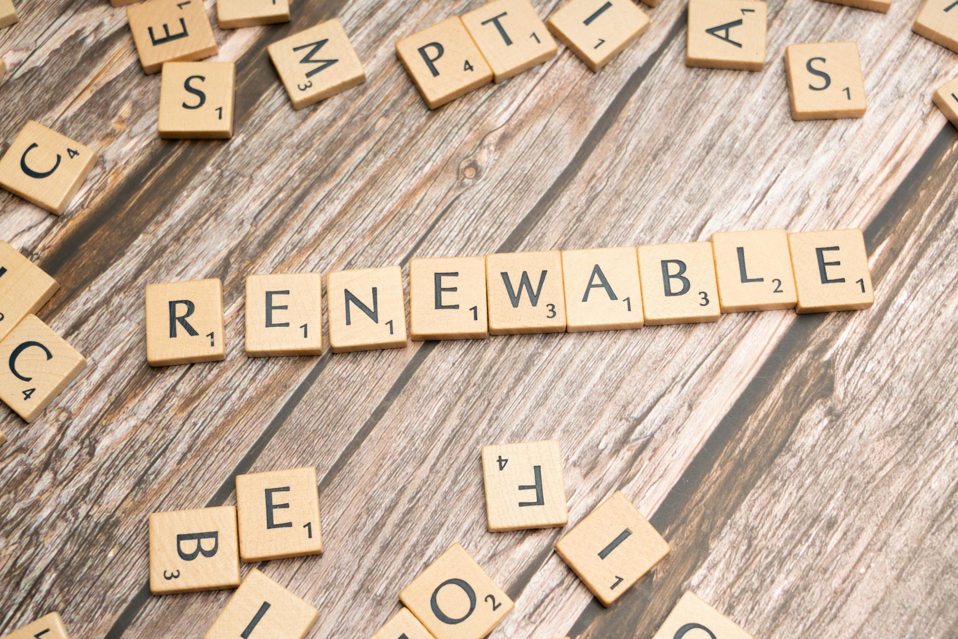 Wooden Scrabble tiles on a wooden table spell 'Renewable' emphasizing sustainability.