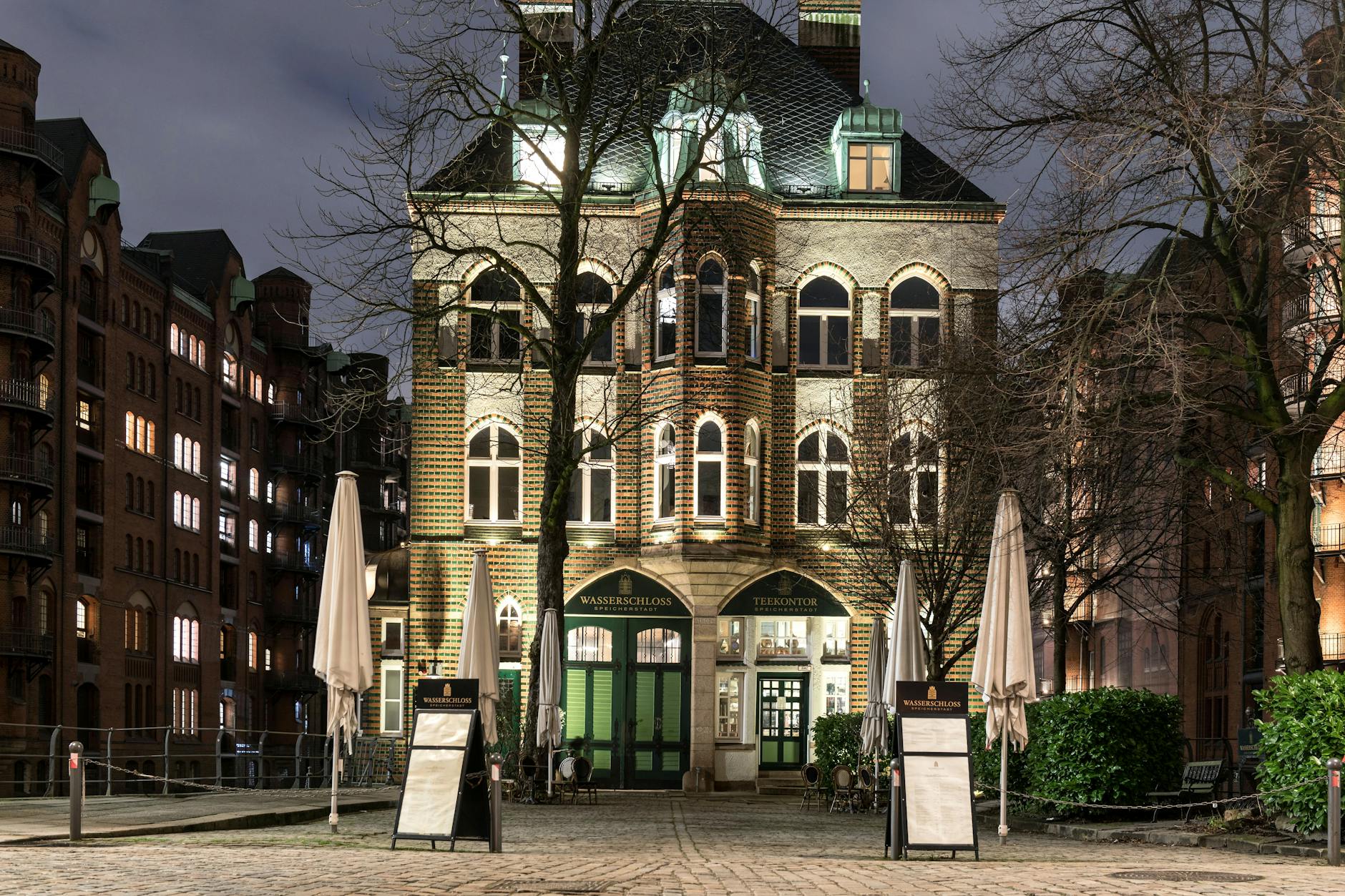 Night view of Wasserschloss in Hamburg's historic Speicherstadt, beautifully lit with a classic facade.