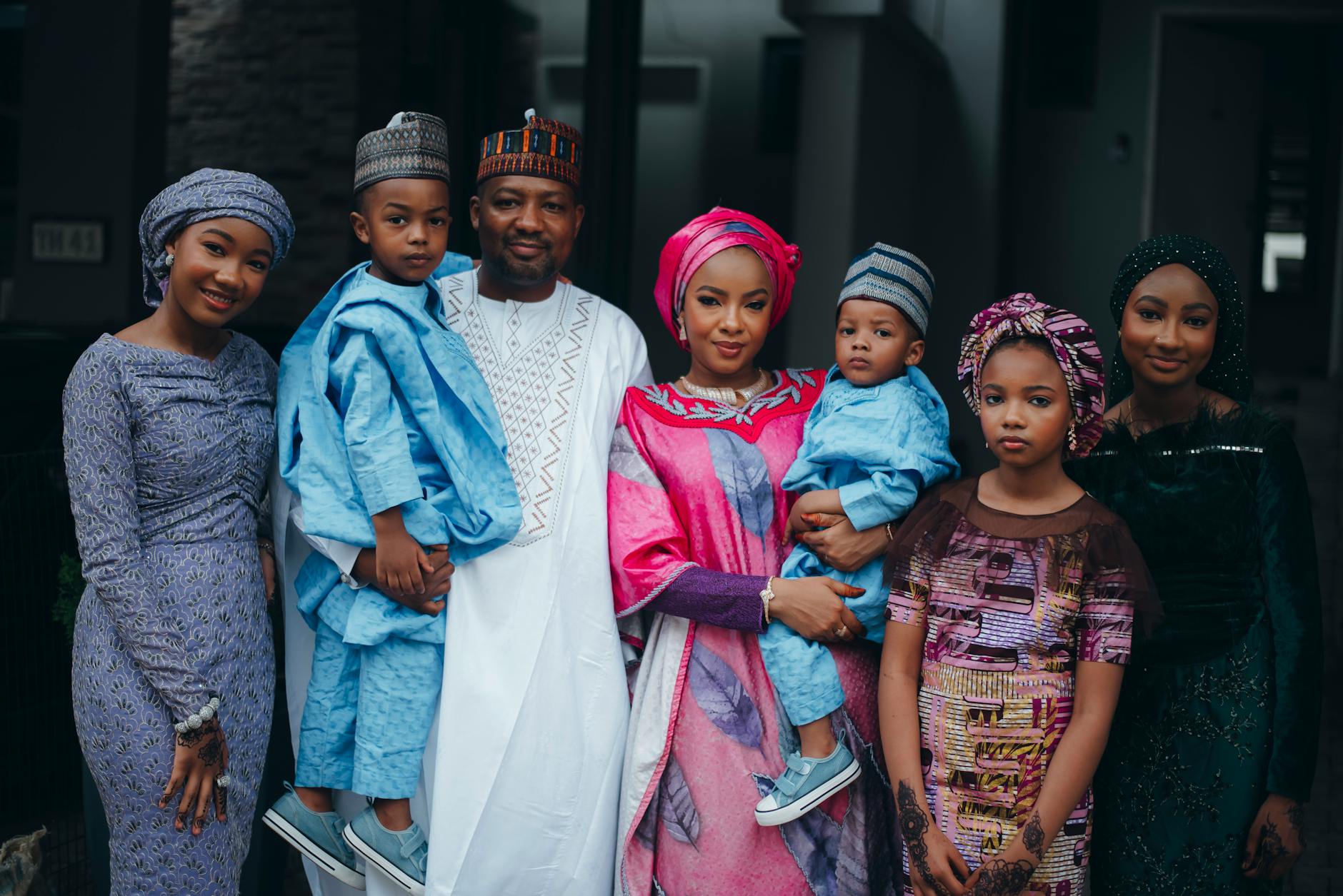 A family of seven posing in colorful traditional African attire, showcasing culture and unity.