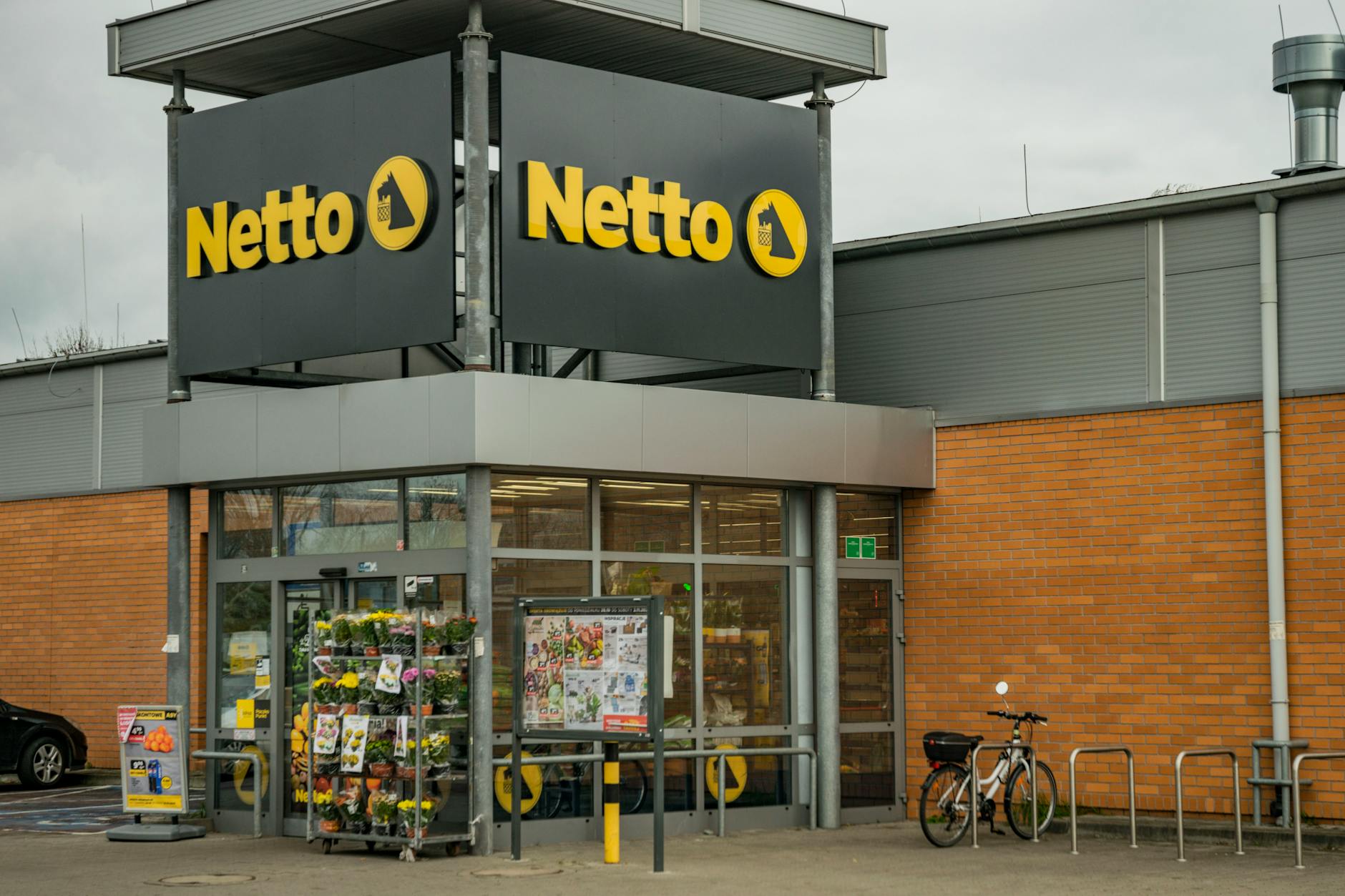 Exterior view of a Netto store with bicycles and a brick facade.