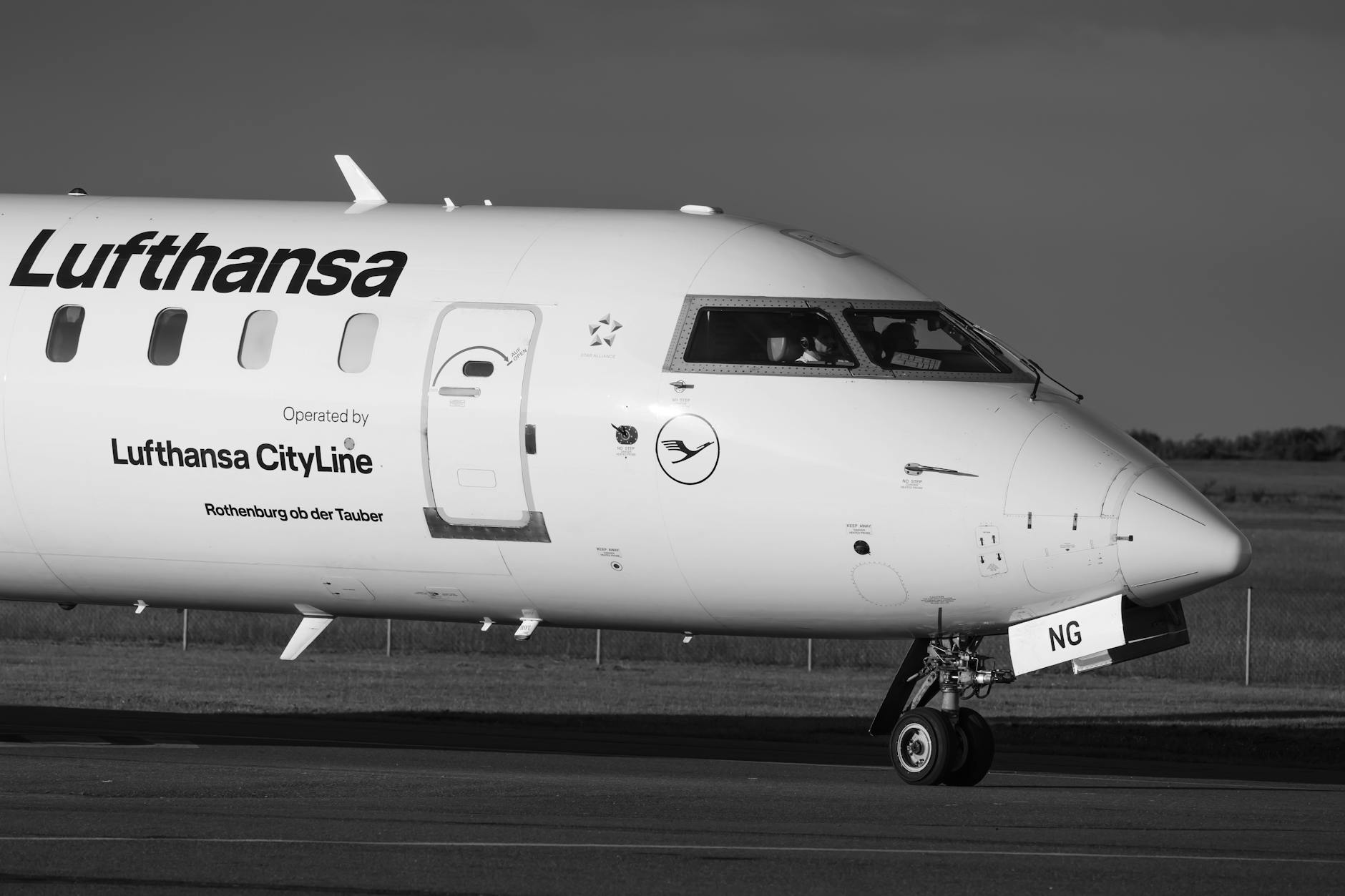 Black and white image of a Lufthansa CityLine aircraft taxiing on a runway.