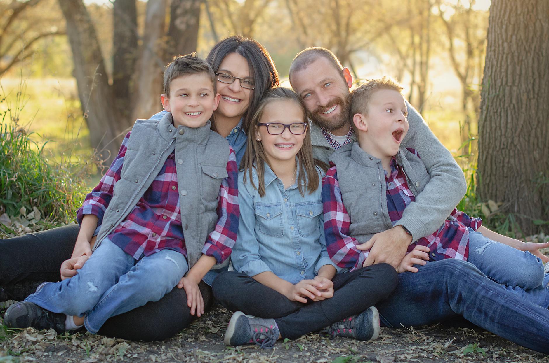 A joyful family portrait in matching outfits enjoying a sunny day outdoors.