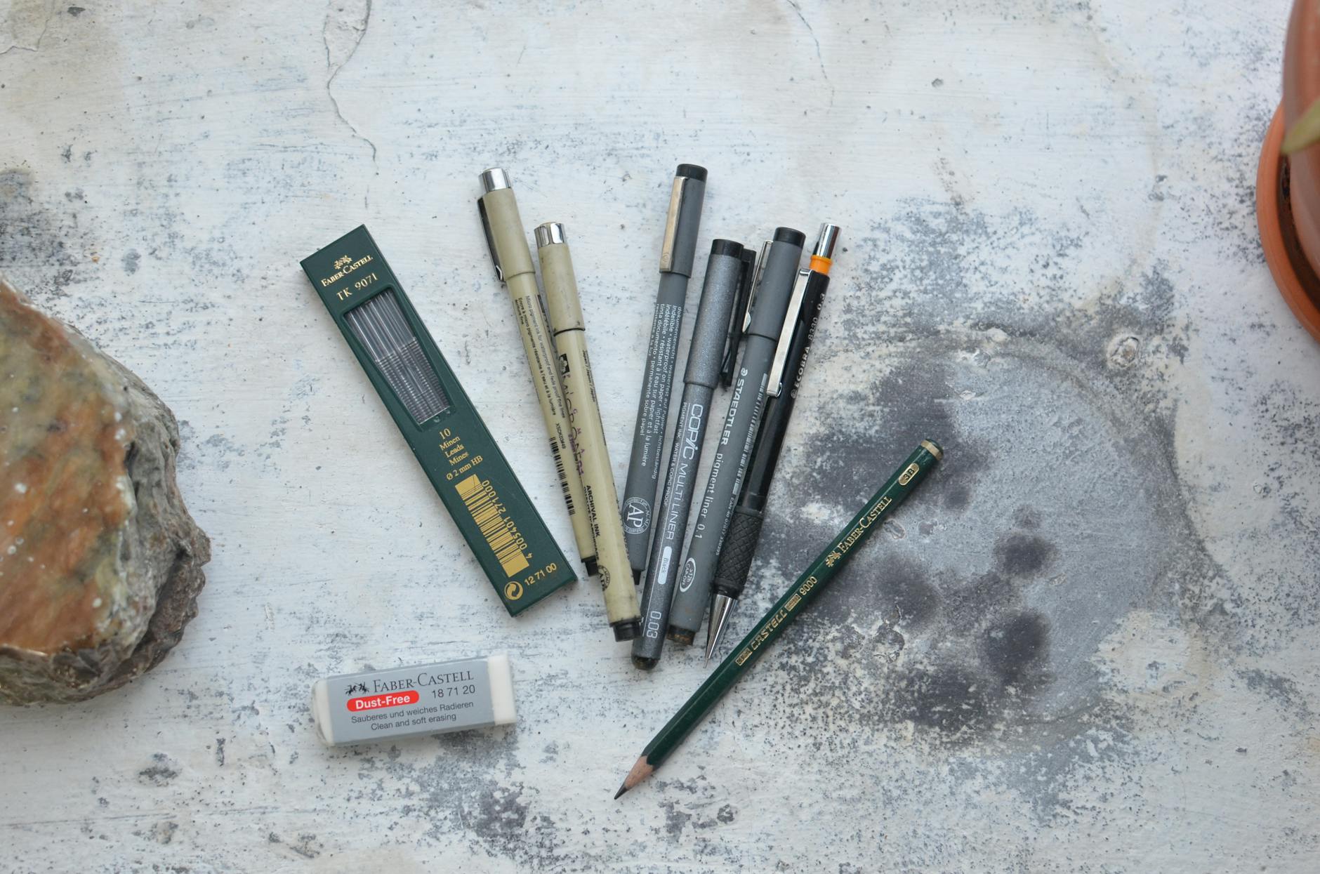 Top view of pencils and pens for art class placed on weathered surface with spots